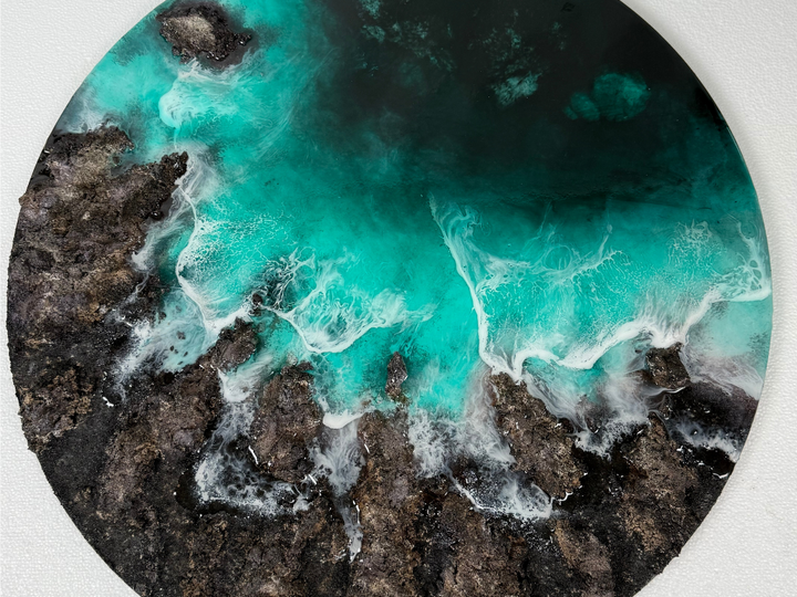 Cuadro redondo de Ocean Art en resina epoxi: mar turquesa con espuma entre rocas oscuras