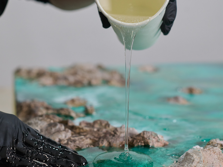 Resina epoxi transparente vertida sobre una obra de Ocean Art con rocas y agua turquesa