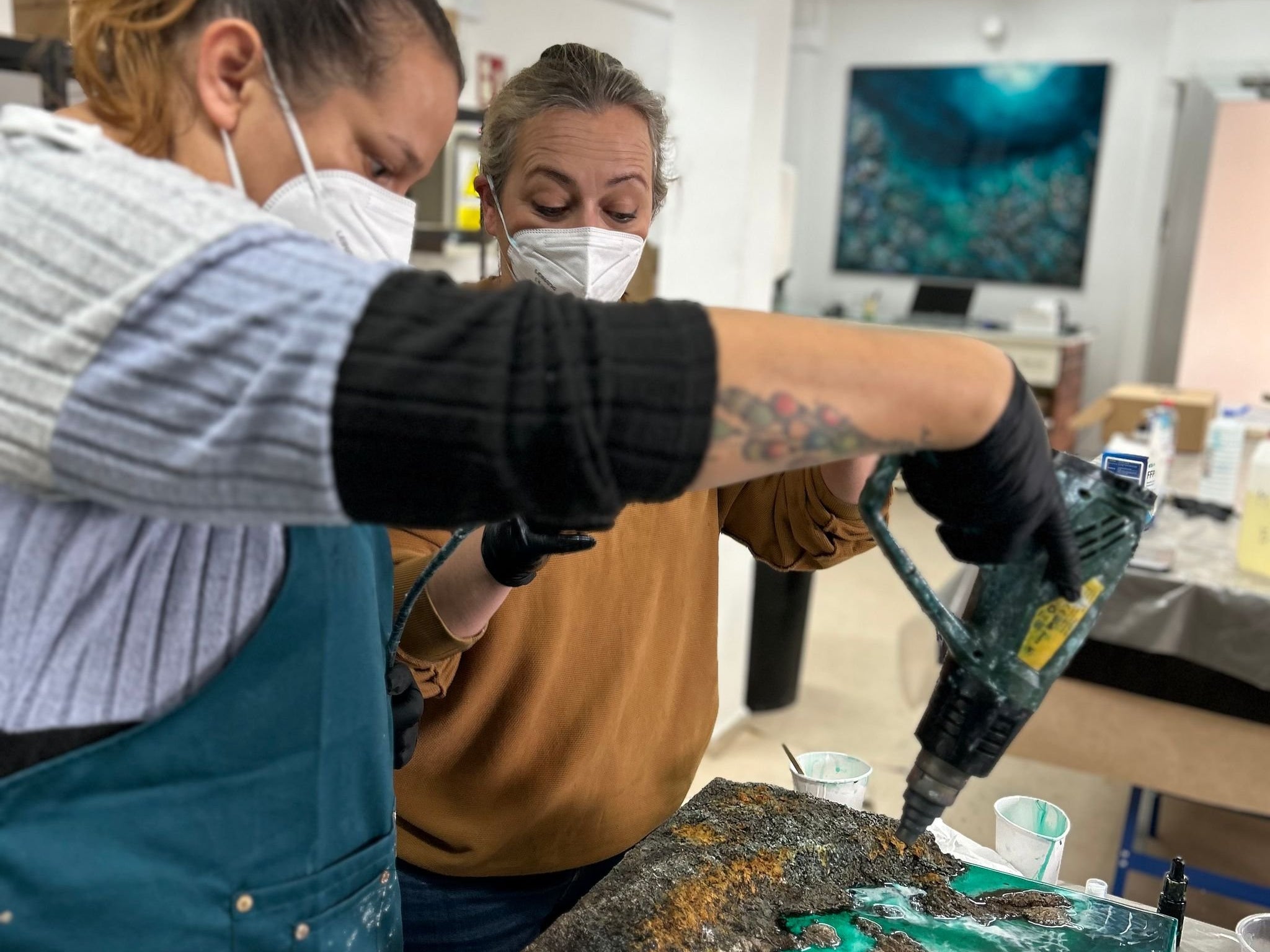 Alumnas trabajando la resina con soplete sobre una obra turquesa