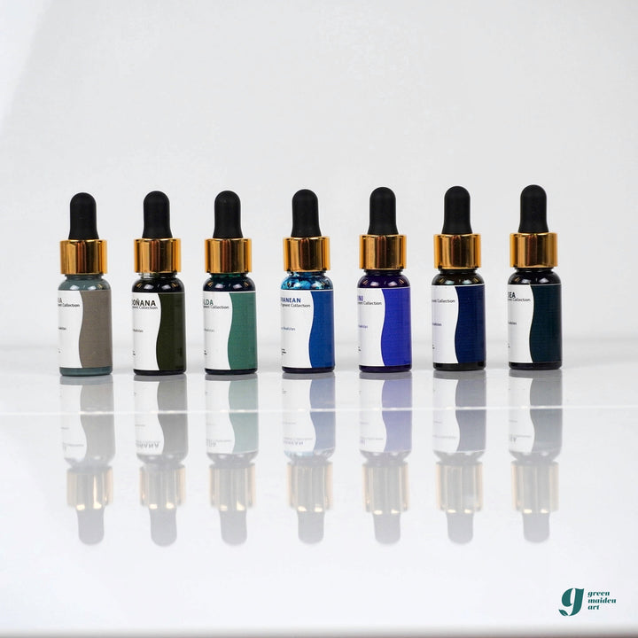 Aqua Pigments Collection: los siete pigmentos líquidos de tonos azules y verdes en fila sobre fondo blanco